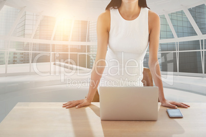 Composite image of portrait of businesswoman with laptop standing at table