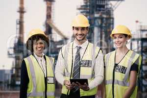 Composite image of portrait of architects in reflective clothing holding tablet computer