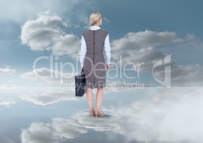 Businesswoman holding briefcase under sky clouds