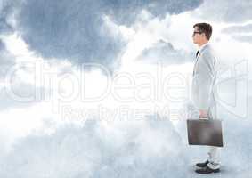 Businessman holding briefcase under sky clouds