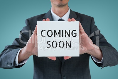 Business man holding a card with coming soon text