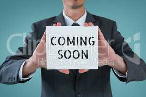 Business man holding a card with coming soon text