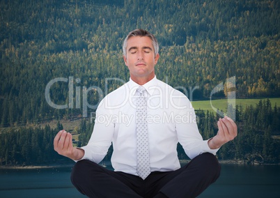 Business man meditating against trees and river