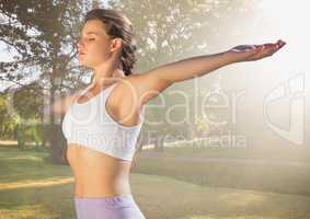 Woman arms outstretched against blurry park with flare