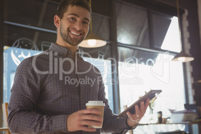 Portrait of happy man using tablet while having coffee