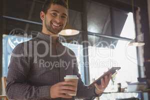 Portrait of happy man using tablet while having coffee