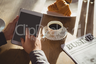 Cropped hands of businessman using tablet in cafe