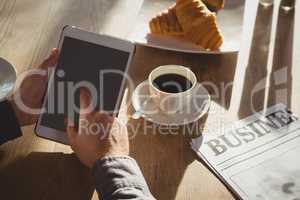 Cropped hands of businessman using tablet in cafe