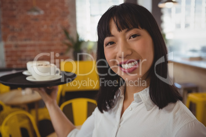 Portrait of smiling waitress with coffee cups