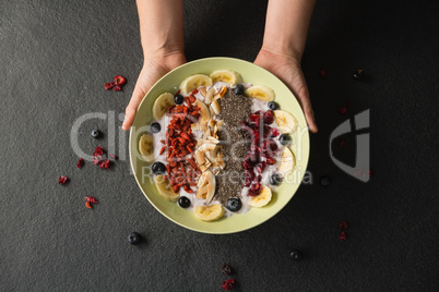 Hands holding a bowl of fruit cereal