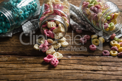 Scattered honeycomb cereals from jar on wooden table