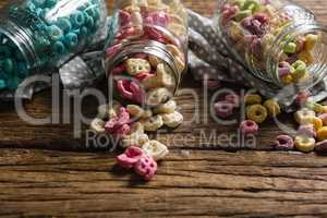 Scattered honeycomb cereals from jar on wooden table