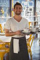 Portrait of waiter holding tray in cafe