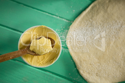 Overhead view of butter in bowl by rolled dough