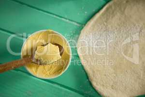 Overhead view of butter in bowl by rolled dough