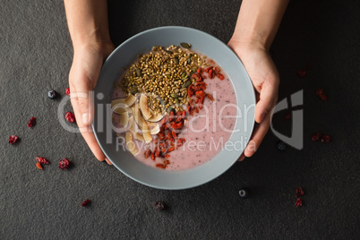 Hands holding a bowl of fruit cereal