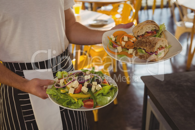 Mid section of waiter serving food