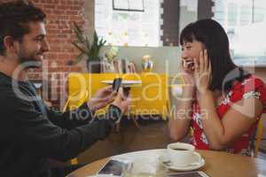 Smiling man gifting ring to girlfriend
