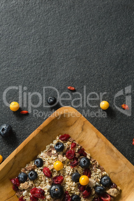 Plate of breakfast cereal with fruits on black background