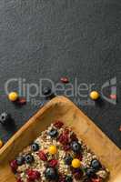 Plate of breakfast cereal with fruits on black background