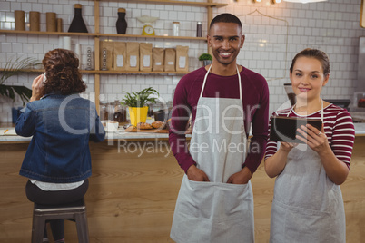 Portrait of owner with man holding tablet in cafe