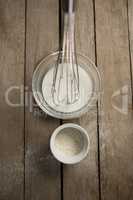 Directly above shot of milk with wire whisk and flour in container