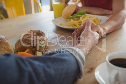 Cropped image of couple holding hands in cafe
