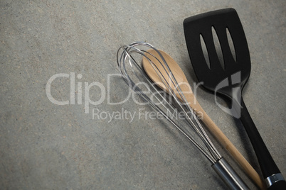 High angle view of wire whisk and wooden spoon by spatula