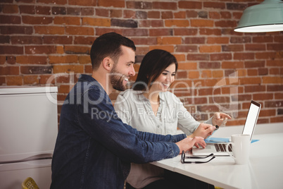 Executives discussing over laptop at desk