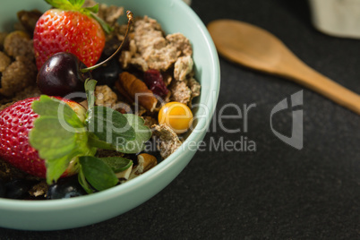 Bowl of breakfast cereals with fruits on black background