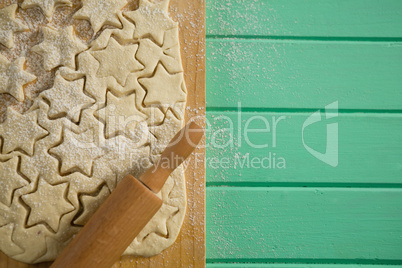 Overhead view of star shape cookies on dough and rolling on cutting board