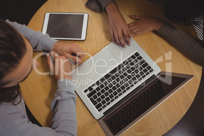 High angle view of friends using laptop at table