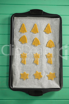 Overhead view of various shape raw cookies in baking tray