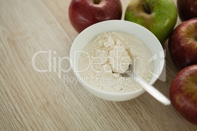 Close up of flour in bowl by apples