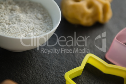 High angle view of flour in bowl by pasty cutters and dough