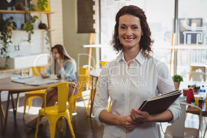 Portrait of waitress with menu in cafe