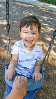 Adorable Chinese and Caucasian Young Boy Having Fun in the Swing
