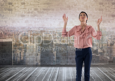 Businesswoman in front of brick wall and city with hands open