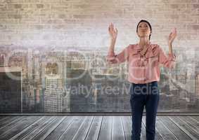 Businesswoman in front of brick wall and city with hands open