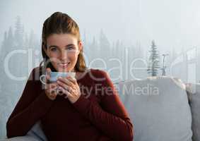 Woman with cup on couch in misty forest