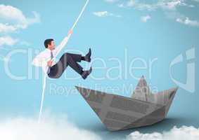 Businesman swinging on rope with paper boat in sky