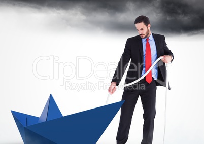 Businessman with paper boat in sky clouds pulling rope