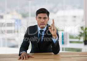 Business man pointing up while sits at his desk in office
