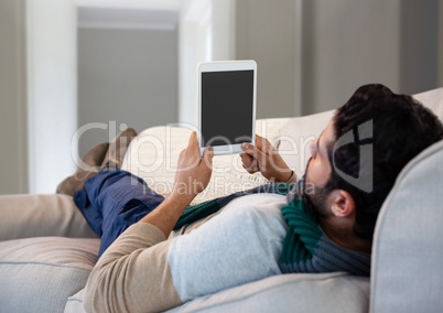 Man in Autumn with tablet on couch at home