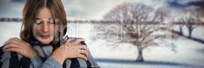 Woman wearing scarf keeping warm in snow landscape with bare tree