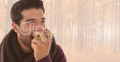 Man in Autumn eating apple in bright forest