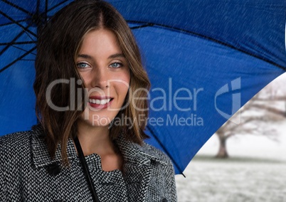 Woman in coat with blue umbrella in snow landscape
