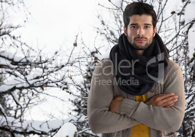 Man wearing scarf with arms folded in snow forest