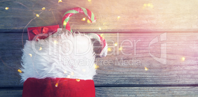 Wrapped gift box and candy cane in stocking against wooden wall
