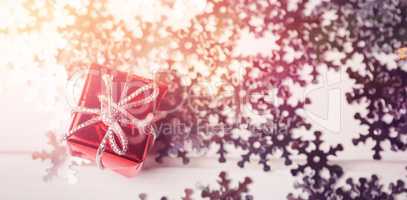 Small wrapped gift box and snowflake scattered on wooden table